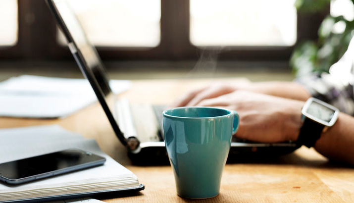 Kontaktaufnahme für IT-Schulungen – Dozent arbeitet am Notebook mit Kaffeetasse